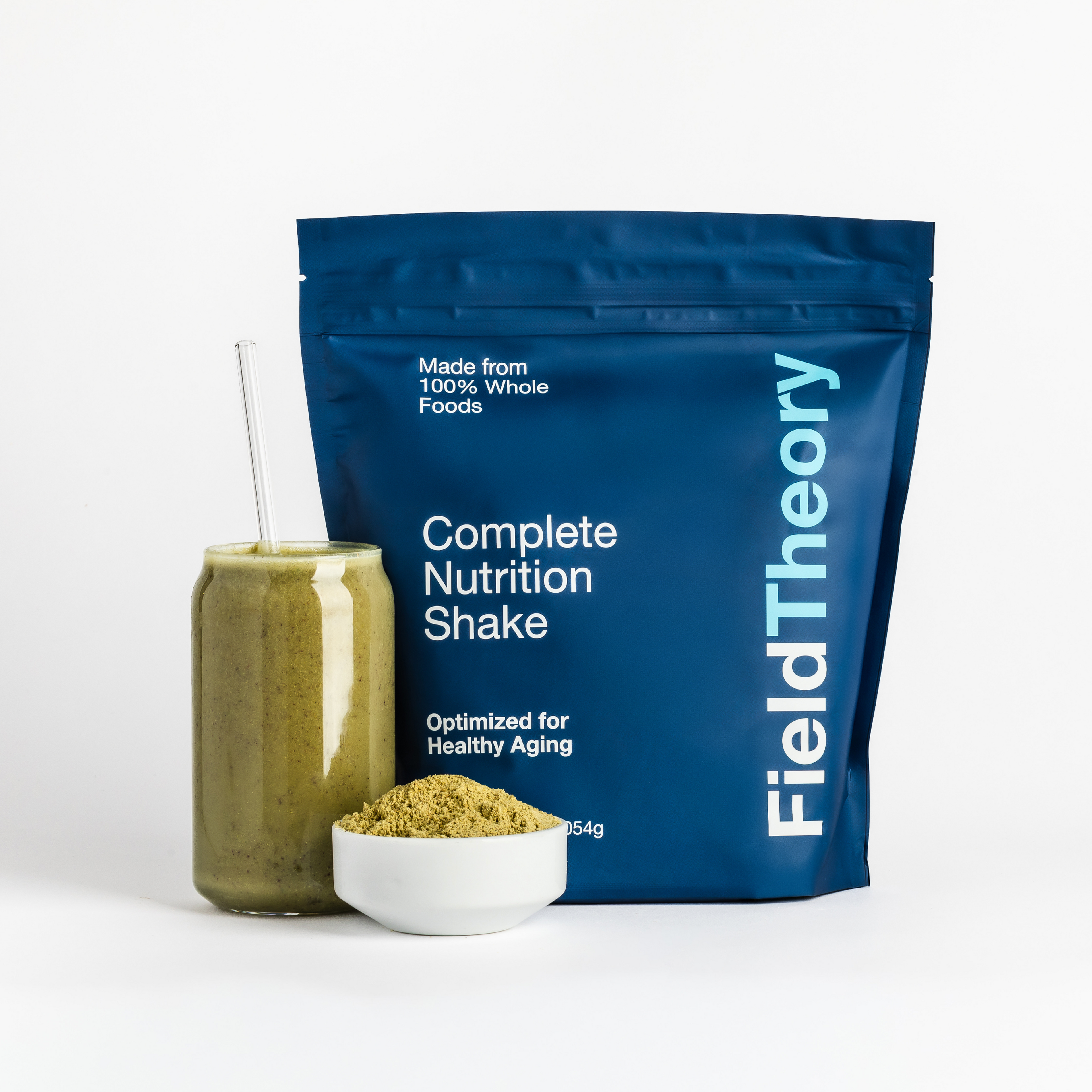 Field Theory complete nutrition shake package with a glass of shake and bowl of powder on a white background