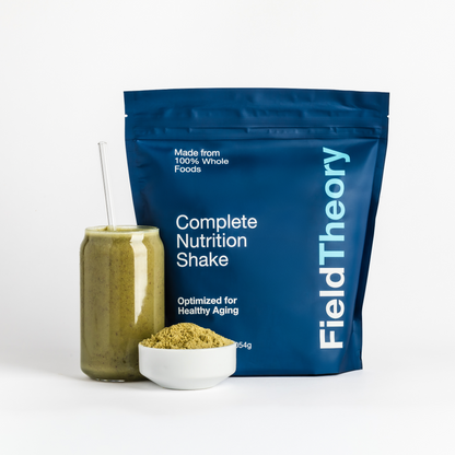 Field Theory complete nutrition shake package with a glass of shake and bowl of powder on a white background